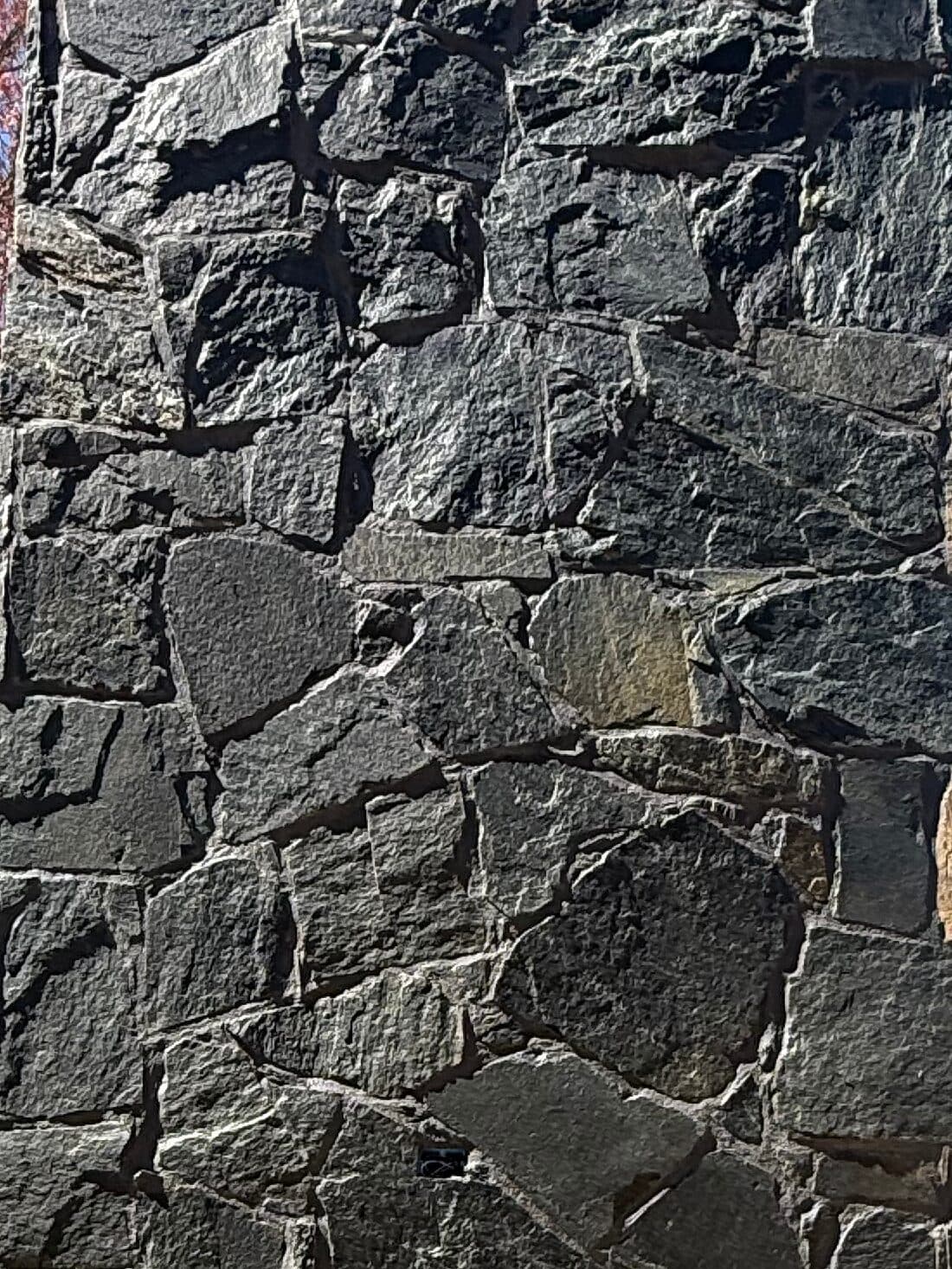 Close view of dark irregular stone laid on a chimney face