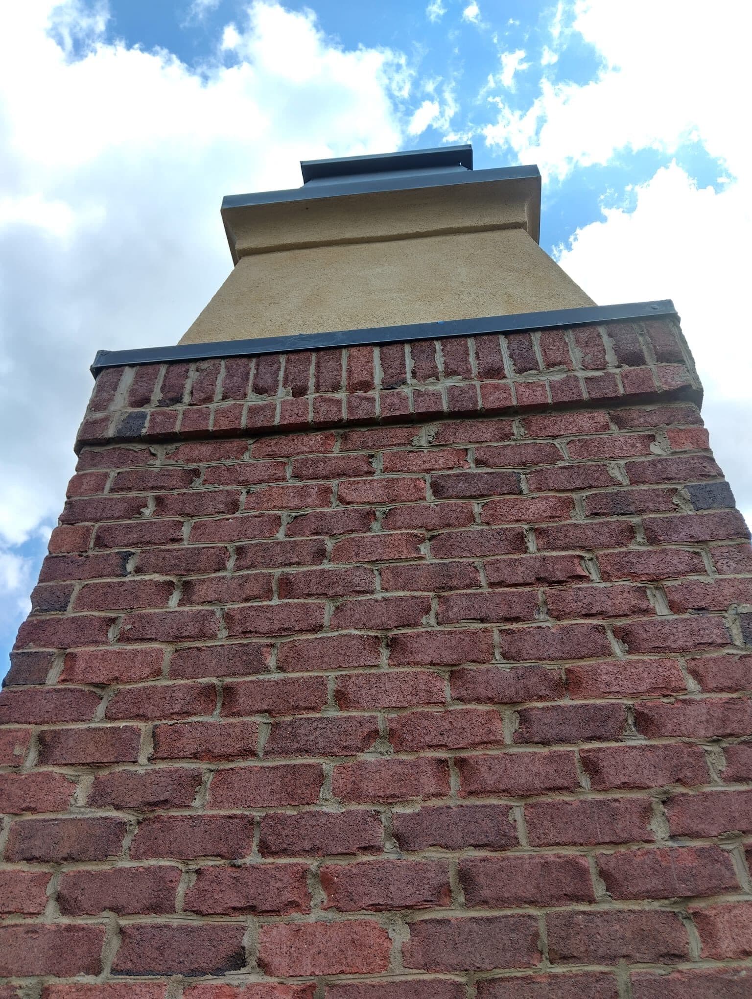 Red brick chimney with a new metal drip cap, seen from below