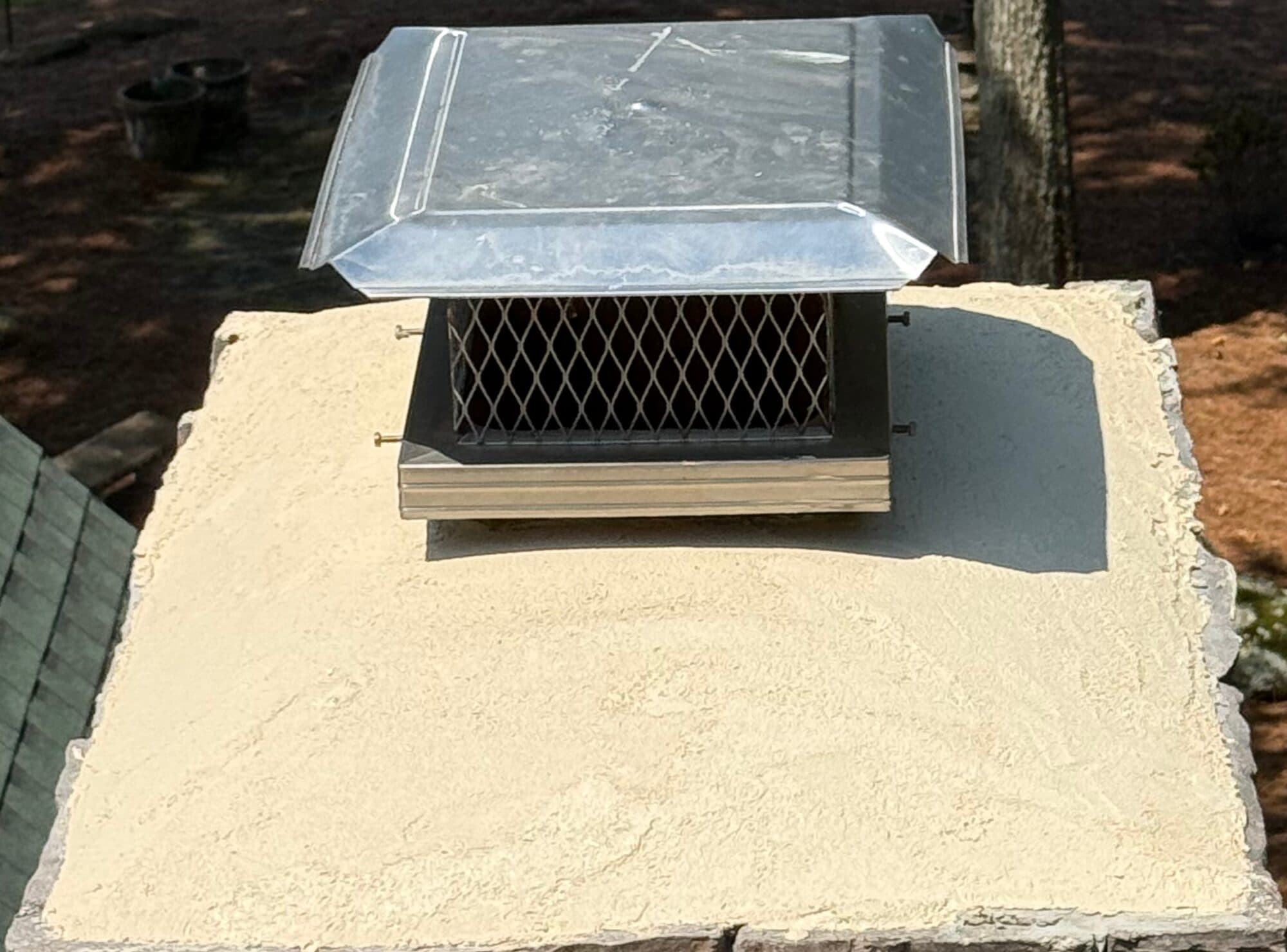 New concrete crown and stainless cap on a stone chimney