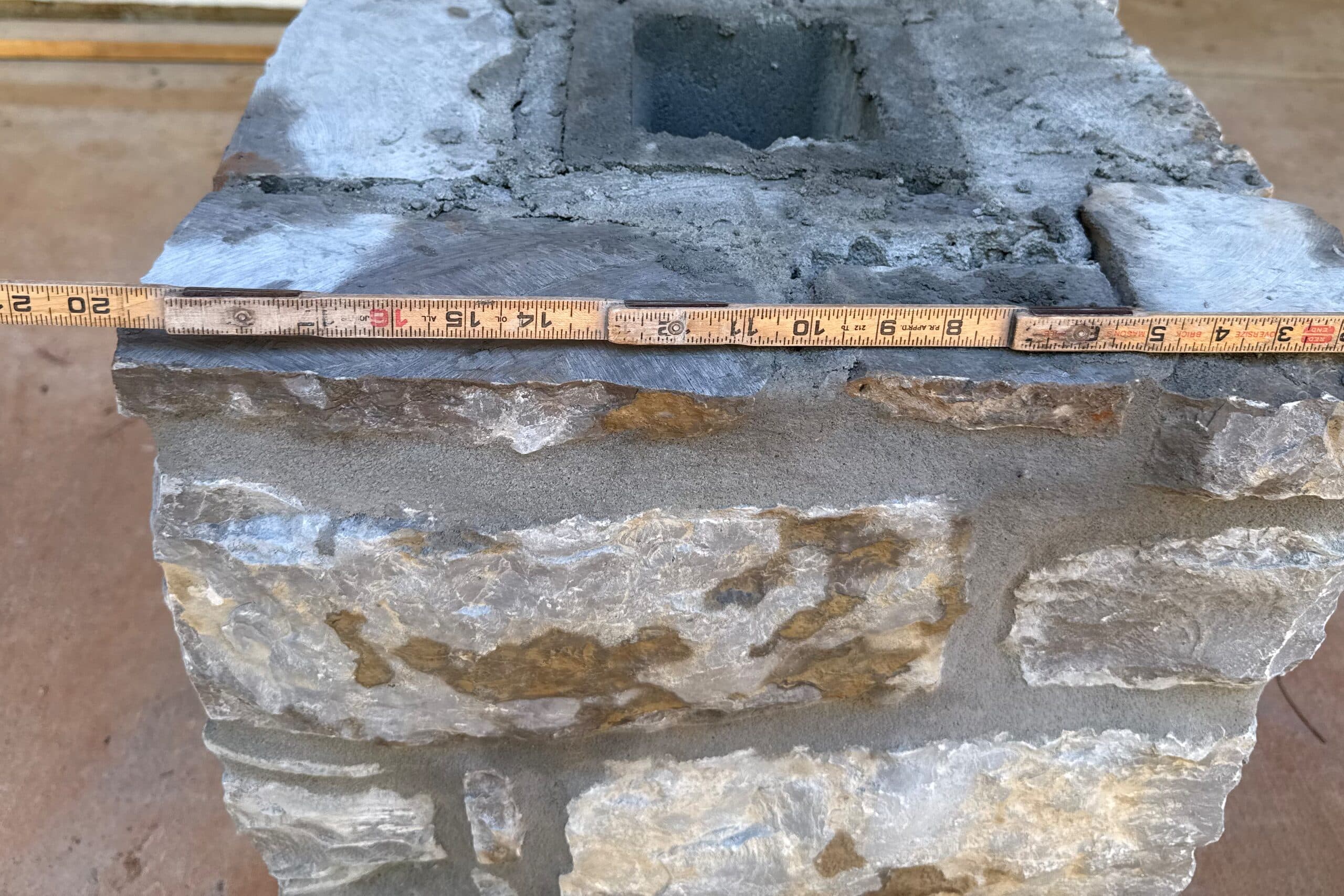 Top of a natural stone column with a folding rule across it