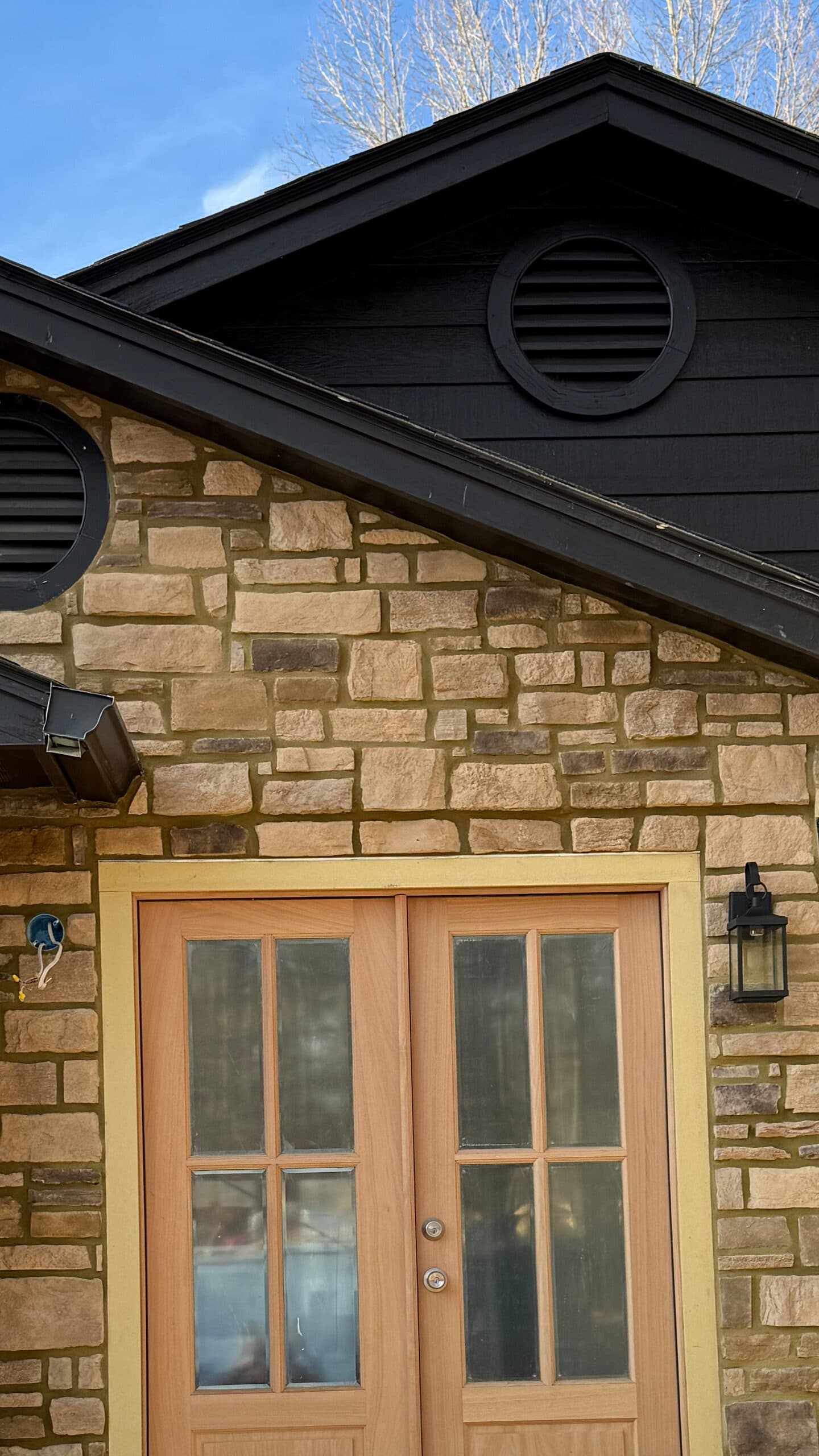 Cut stone veneer around a gable entry with wood double doors